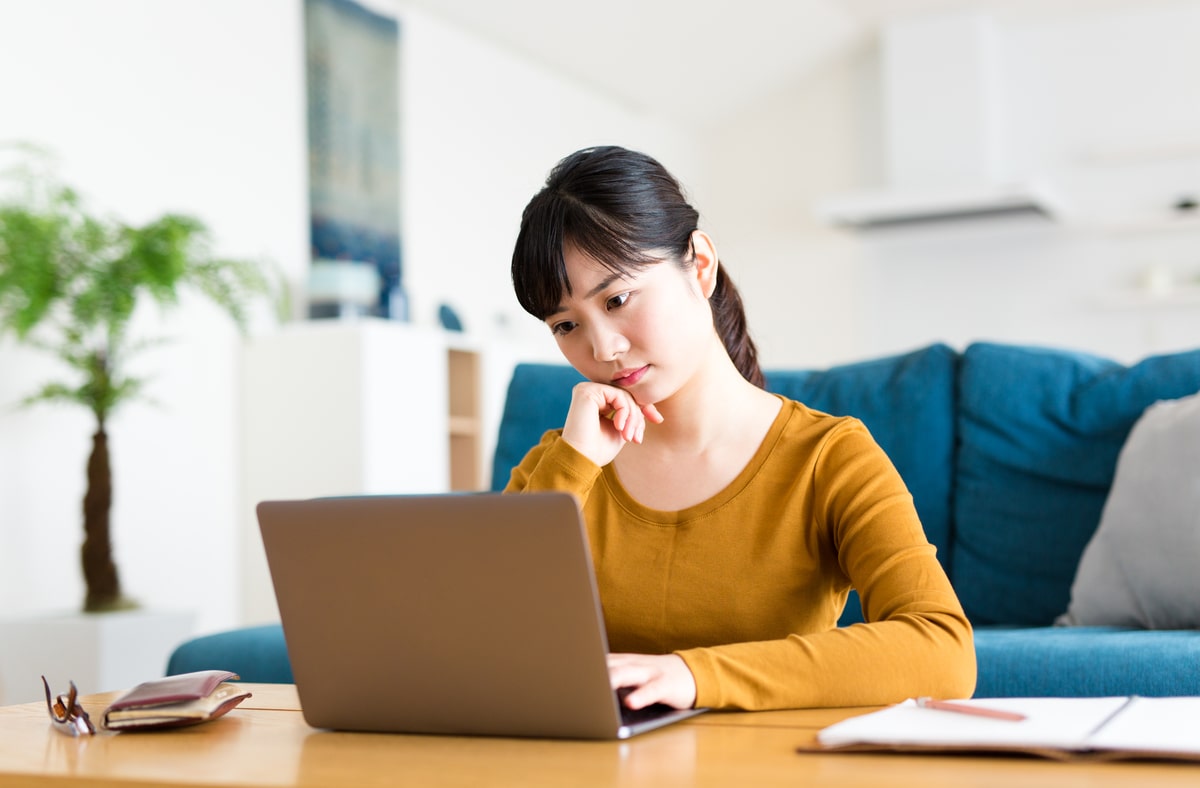 ノートパソコンの前で悩む女性