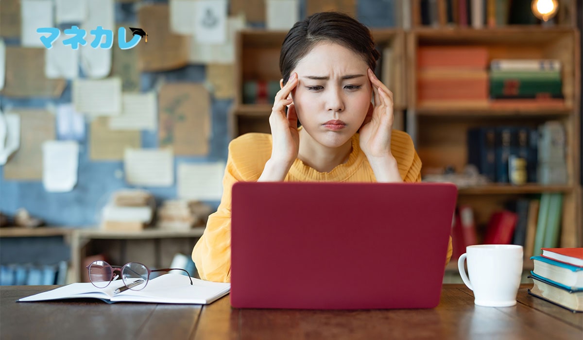 赤いノートパソコンを前に悩む女性